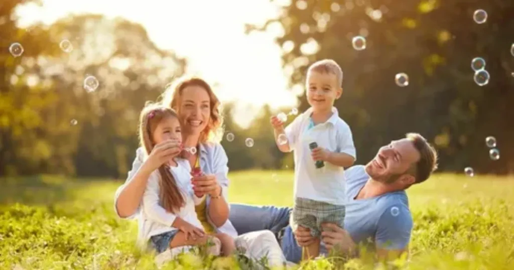 Happy family playing with bubbles in a sunny park